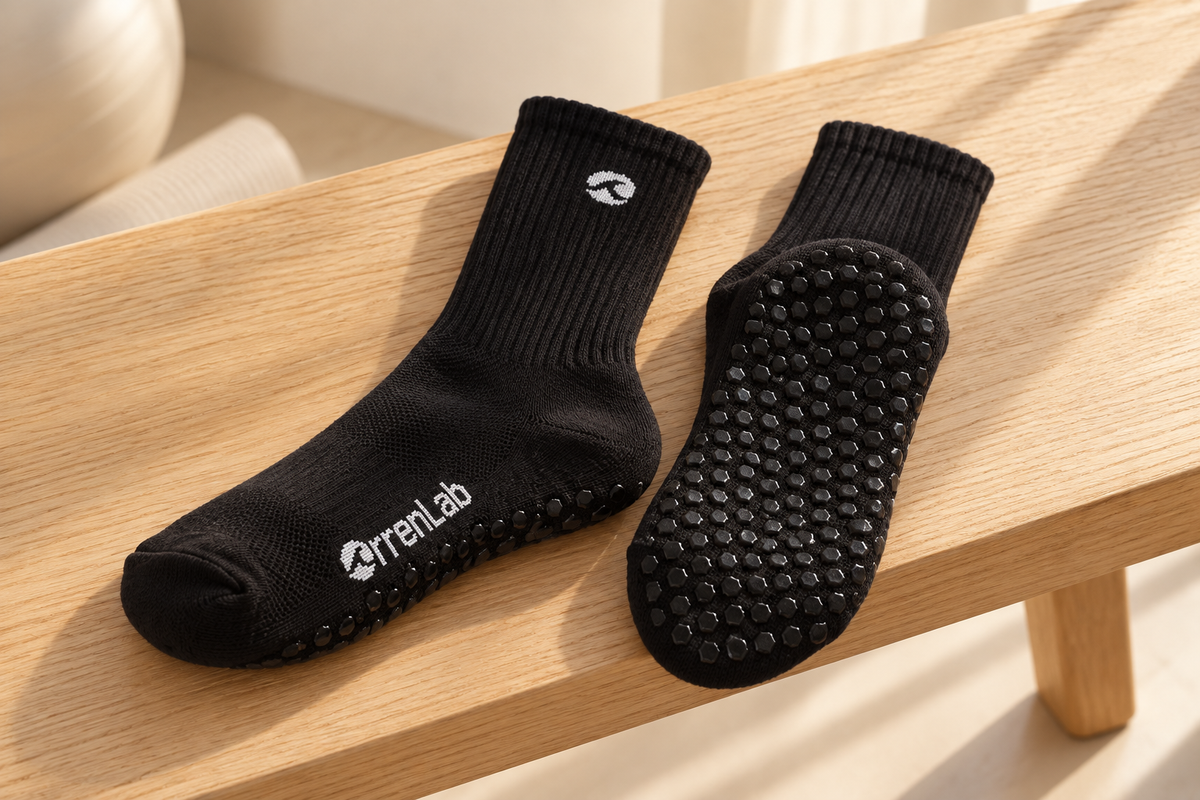 Orrenlab grip socks on an oak bench, showing the ribbed cuff, knit fabric, toe and textured sole.